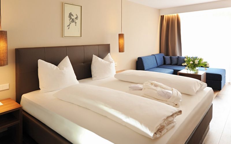 Doppelzimmer Burgund im Hotel Vier Jahreszeiten mit gemütlichem Schlafzimmer, Couch und Bett