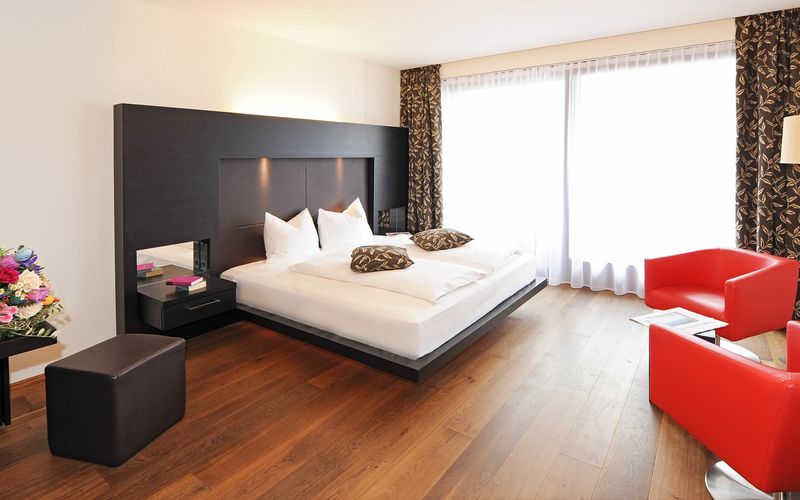 Modernes Designerzimmer im Penthouse mit Doppelbett und Sitzecke im Hotel Vier Jahreszeiten