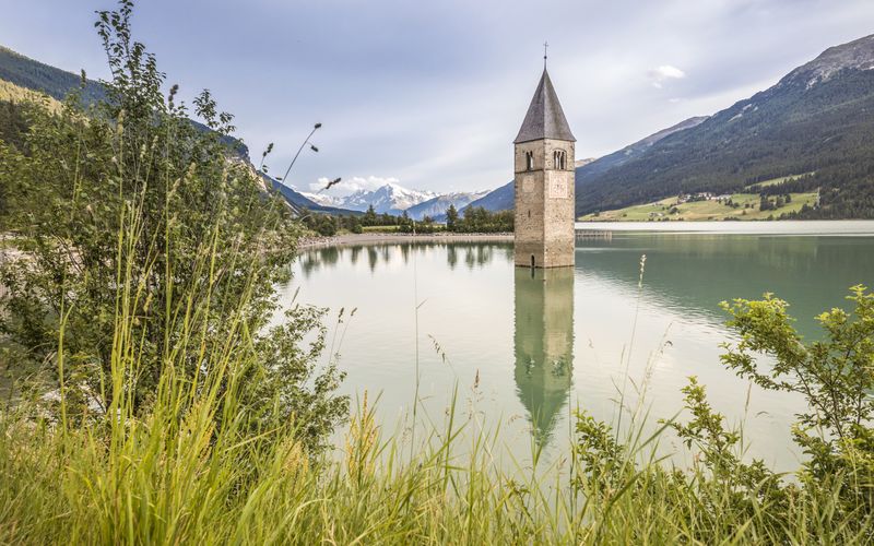 Versunkener Kirchturm im Reschensee im Vinschgau bei Sonnenuntergang