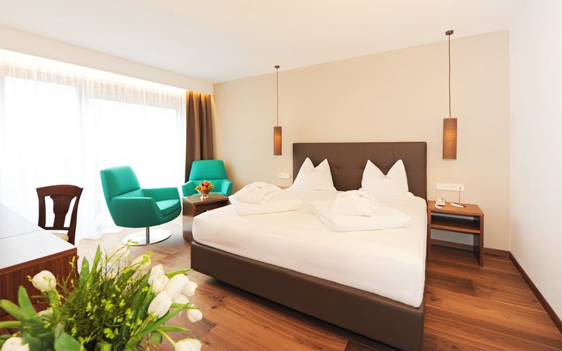 Modernes Doppelzimmer im Hotel Vier Jahreszeiten in Südtirol mit Alpenblick, gemütlichem Bett und Sitzecke