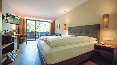 Modernes Doppelzimmer Burgund mit gemütlichem Bett im Hotel Vier Jahreszeiten