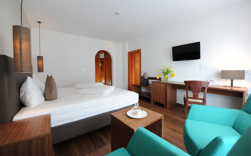 Familienzimmer Alpen im Hotel Vier Jahreszeiten mit gemütlichem Schlafzimmer, Doppelbett und Sitzecke