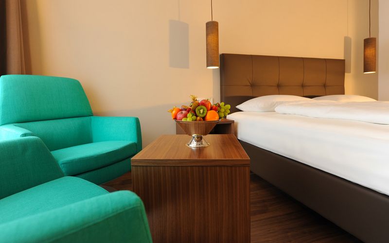 Modern eingerichtetes Doppelzimmer im Hotel Vier Jahreszeiten in den Alpen mit gemütlicher Sitzecke und Doppelbett