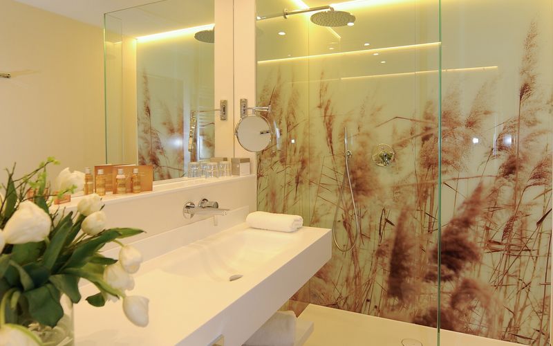 Modernes Badezimmer mit Glasdusche, Blumen und Beleuchtung