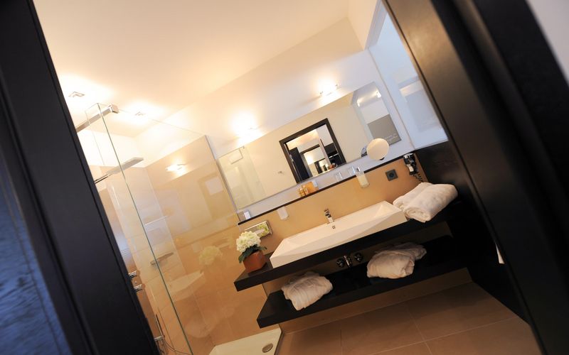 Modernes Penthouse-Badezimmer im Hotel Vier Jahreszeiten in Südtirol mit freistehender Badewanne und stilvoller Einrichtung