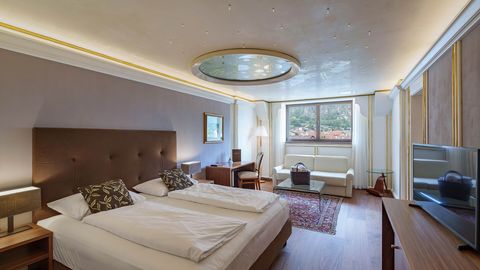 Modernes Hotelzimmer mit Doppelbett, Sofa, Schreibtisch und Fenster mit Bergblick