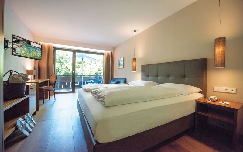 Modernes Doppelzimmer Burgund mit gemütlichem Bett im Hotel Vier Jahreszeiten