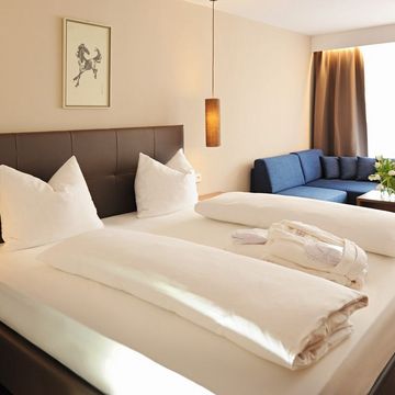 Modernes Doppelzimmer Burgund im Hotel Vier Jahreszeiten in Südtirol mit gemütlichem Bett und stilvollem Interieur