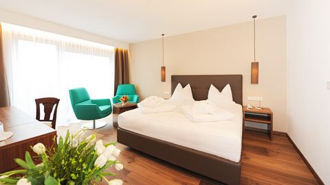 Modernes Doppelzimmer im Hotel Vier Jahreszeiten in Südtirol mit Alpenblick, gemütlichem Bett und Sitzecke
